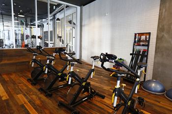 Yoga studio with stationary bikes, large mirror, and wood panel flooring